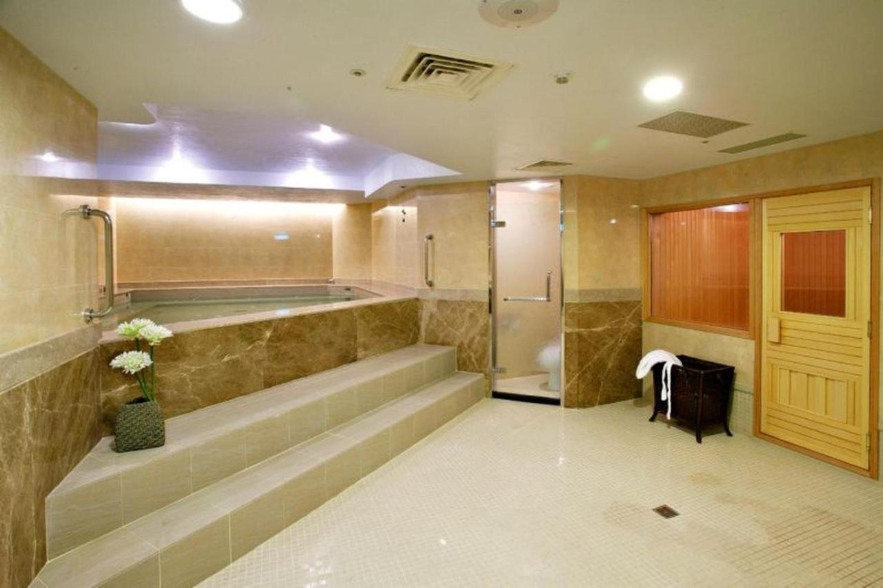 เอเวอร์กรีน เลาเรล โฮเต็ล ไทชุง Hotel ไถจง ภายนอก รูปภาพ The photo shows a spacious and well-lit spa or wellness area. It features a large, recessed hot tub with steps leading up to it, surrounded by beige marble walls. There's a shower area enclosed in glass, and to the right, a wooden sauna or steam room