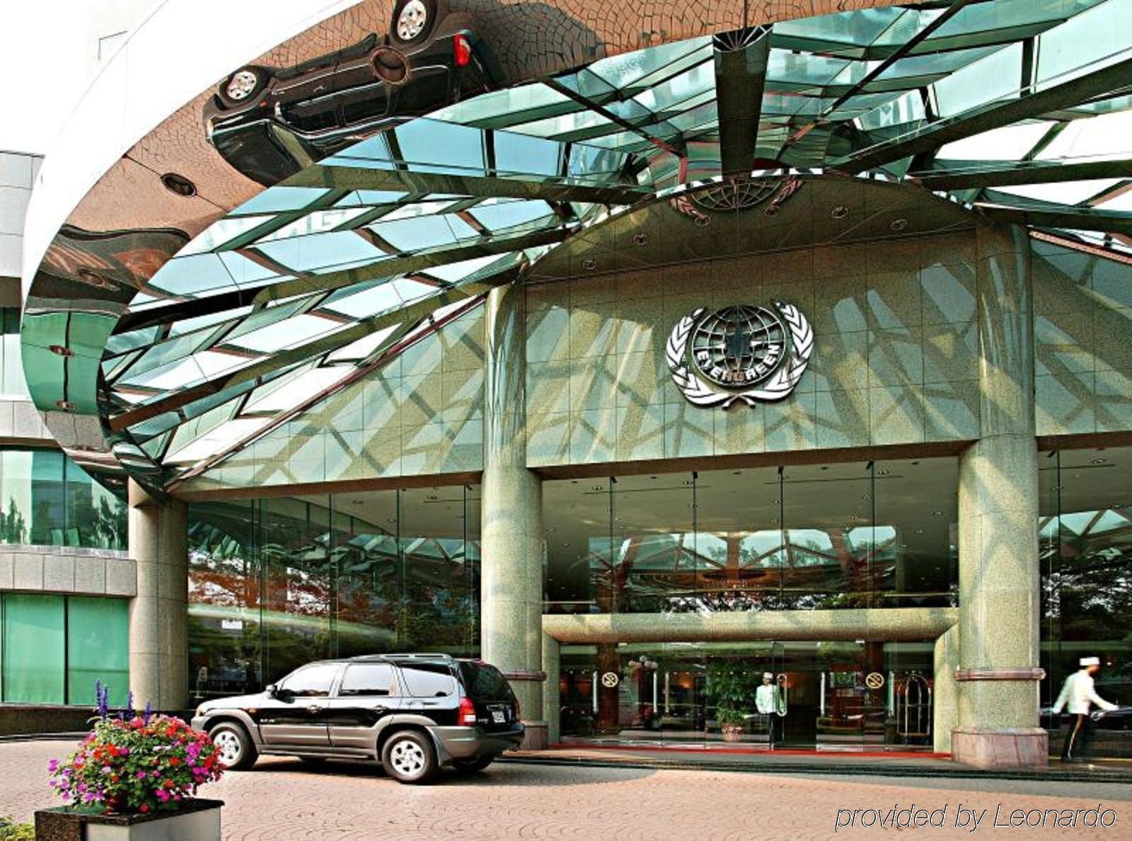 เอเวอร์กรีน เลาเรล โฮเต็ล ไทชุง Hotel ไถจง ภายนอก รูปภาพ The photo shows the entrance of a modern building characterized by its glass and metal architecture. The structure features a large, domed roof that reflects light, with a distinctive emblem or logo displayed prominently at the center. In front of th