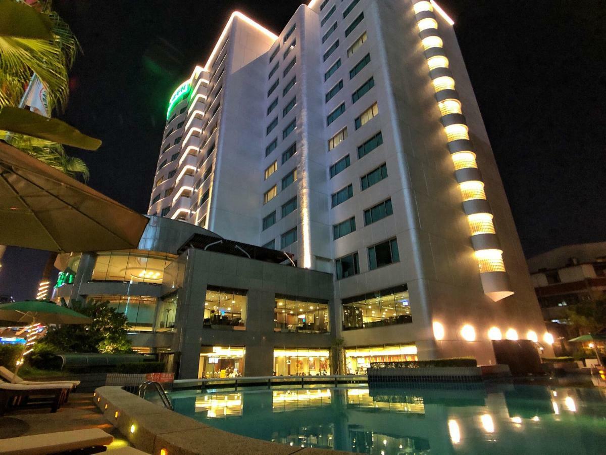 เอเวอร์กรีน เลาเรล โฮเต็ล ไทชุง Hotel ไถจง ภายนอก รูปภาพ The photo shows a tall hotel building at night, illuminated by lights. The architecture appears modern, with several floors and large windows. In the foreground, there is a swimming pool that reflects the lights from the building, creating a serene a