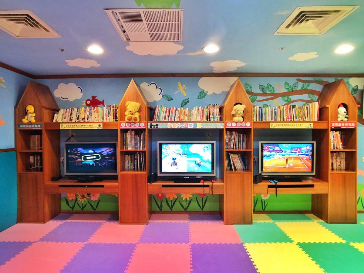 เอเวอร์กรีน เลาเรล โฮเต็ล ไทชุง Hotel ไถจง ภายนอก รูปภาพ The photo shows a colorful and playful room designed for children. In the center, there are three wooden gaming stations, each equipped with a television screen and surrounded by shelves filled with books. The walls are decorated with cheerful images