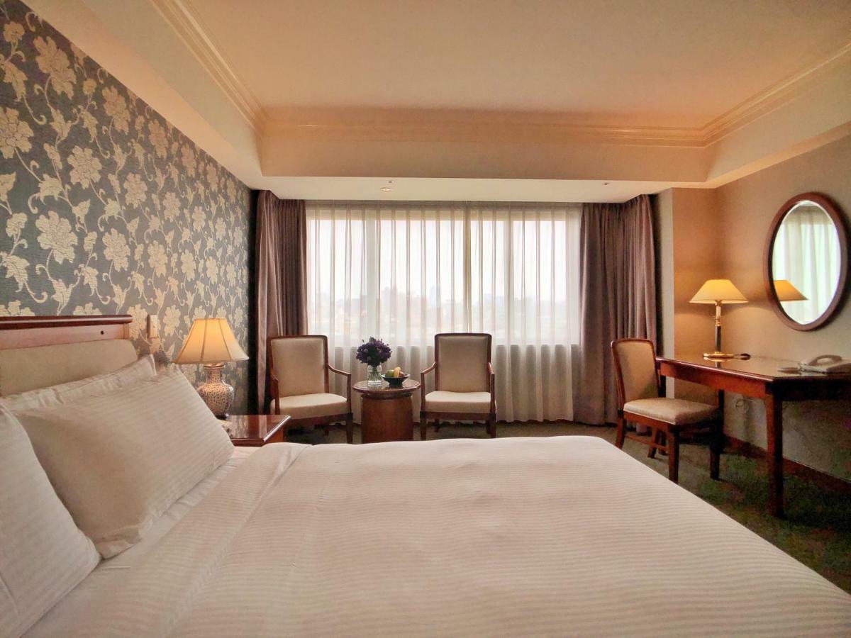เอเวอร์กรีน เลาเรล โฮเต็ล ไทชุง Hotel ไถจง ภายนอก รูปภาพ The photo shows a hotel room with a comfortable and inviting design. There is a large bed with crisp white bedding on the left side of the image. To the right, there are two elegant chairs with a small round table between them, adorned with a bouquet