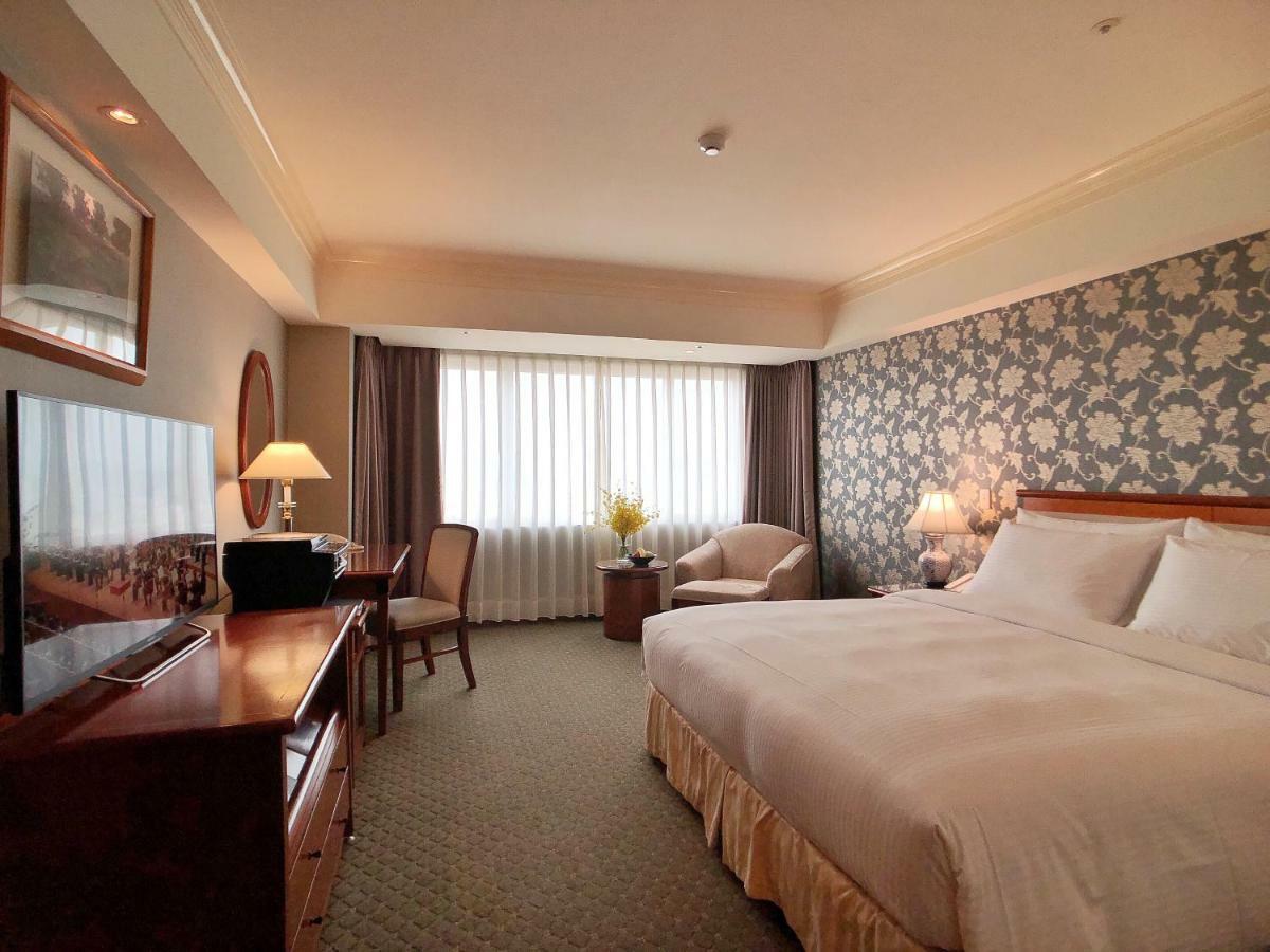 เอเวอร์กรีน เลาเรล โฮเต็ล ไทชุง Hotel ไถจง ภายนอก รูปภาพ The photo shows a hotel room with a spacious layout. It features a large bed with white bedding, bedside lamps, and a decorative headboard. There is a comfortable seating area with an armchair and small table. A desk is present, complete with a lamp 